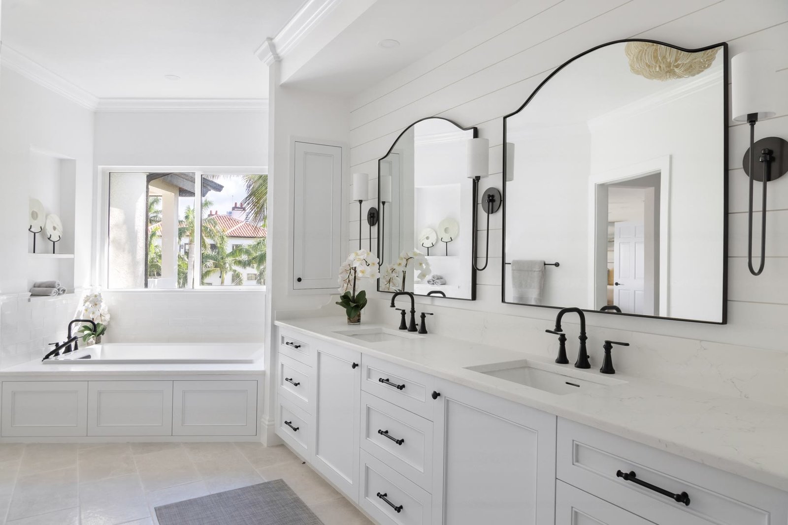 Primary bath double vanity with arched black-framed mirrors and white millwork, St. Armands