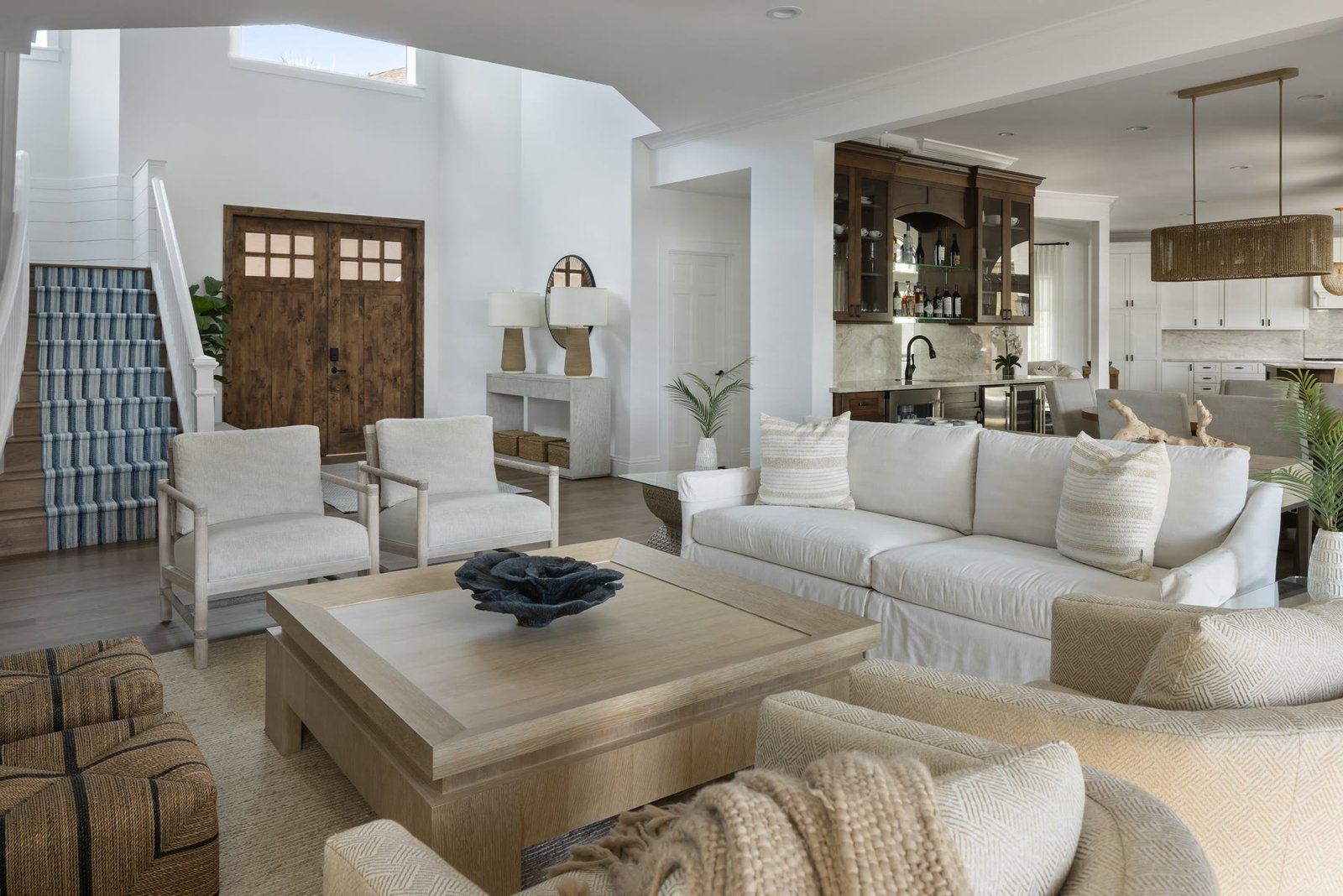 Great room with millwork, a custom wet bar, and a staircase with a blue runner